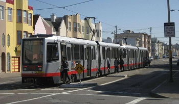 Picture of N Judah train on street with passengers boarding.