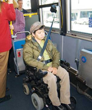 photograph of passenger in wheelchair using the securement area and seatbelt on Muni low-floor bus