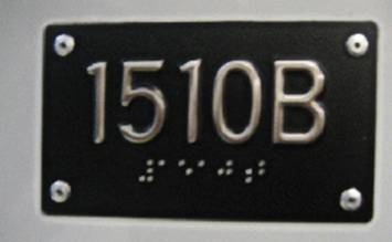 Photograph of accessible light rail vehicle identification plate showing the four digit vehicle identification number in large print, raised letter and Braille formats.
