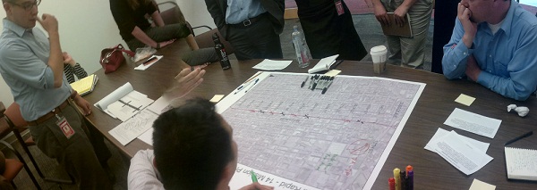 Picture of people standing around a 14 Mission map and discussing route changes