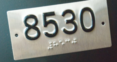 Photograph of vehicle identification number plate that displays number in raised letter and Braille formats for customers with visual disabilities.