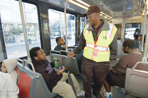 Photograph of Muni Transit Assistance Program personnel talking to customers onboard a light rail train.