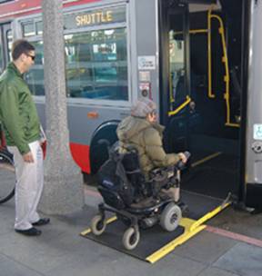 photo of woman in wheelchair using ramp to board shuttle to football game